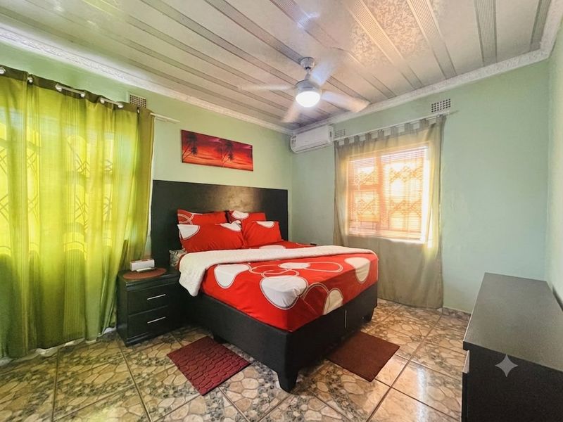 A bedroom featuring tiled flooring, a ceiling fan, and a wall-mounted air conditioning unit.