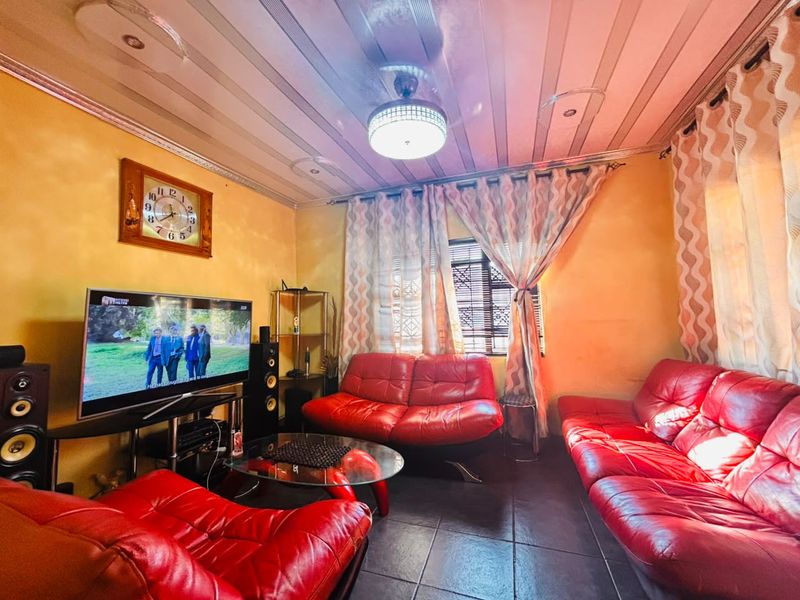 A living room featuring tiled flooring, a ceiling fan, and recessed lighting, currently styled with vibrant red seating.