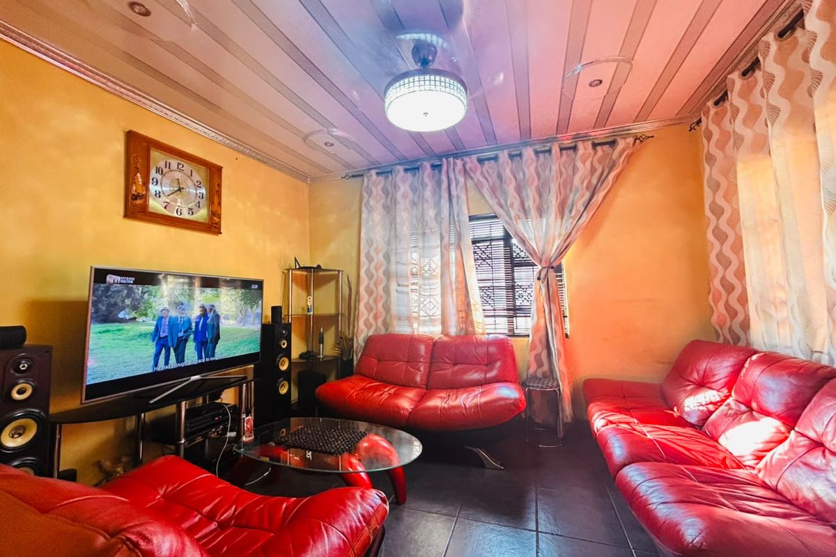 A living room featuring tiled flooring, a ceiling fan, and recessed lighting, currently styled with vibrant red seating.