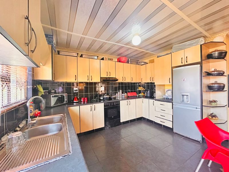 A functional kitchen featuring light wood-tone cabinetry, dark tiled backsplash, double sink, and built-in oven with extractor fan.