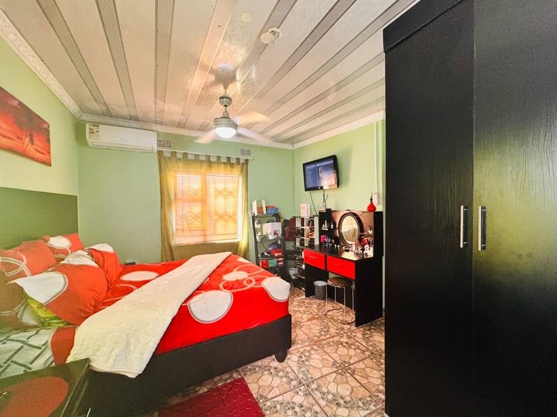A bedroom featuring tiled flooring, a ceiling fan, and a wall-mounted air conditioning unit.