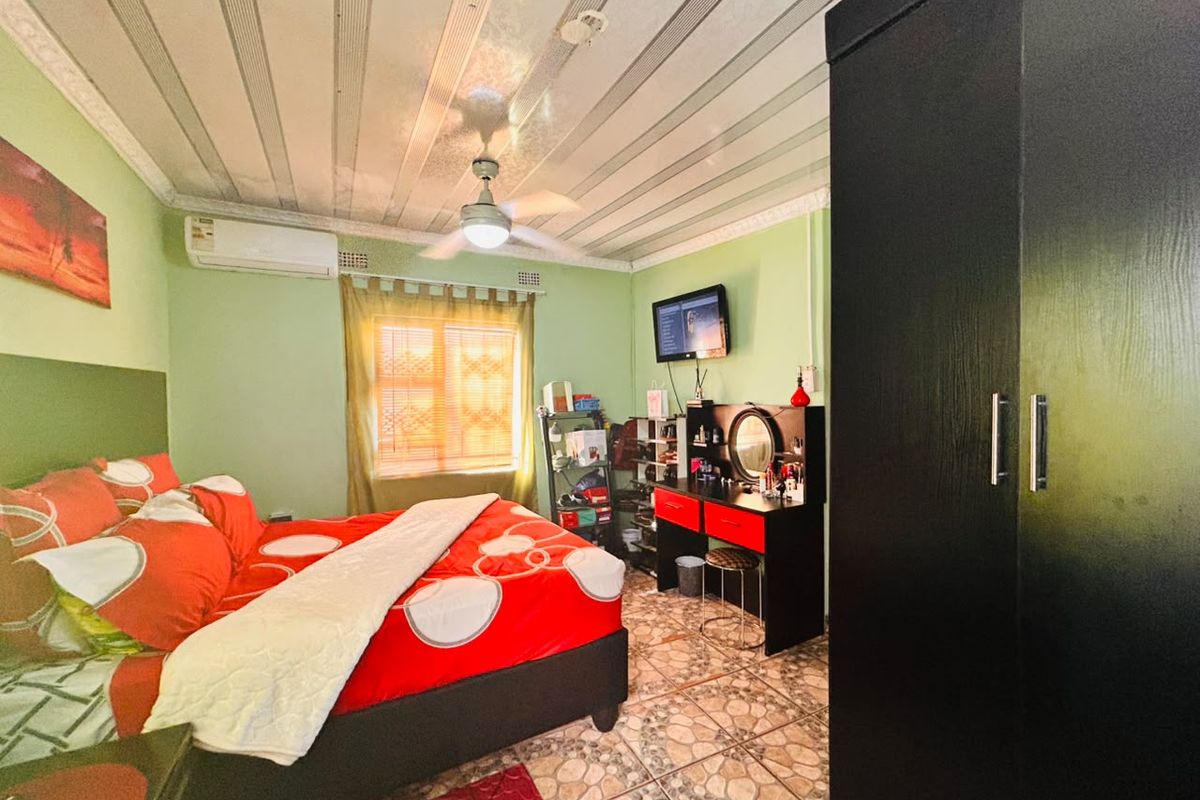 A bedroom featuring tiled flooring, a ceiling fan, and a wall-mounted air conditioning unit.