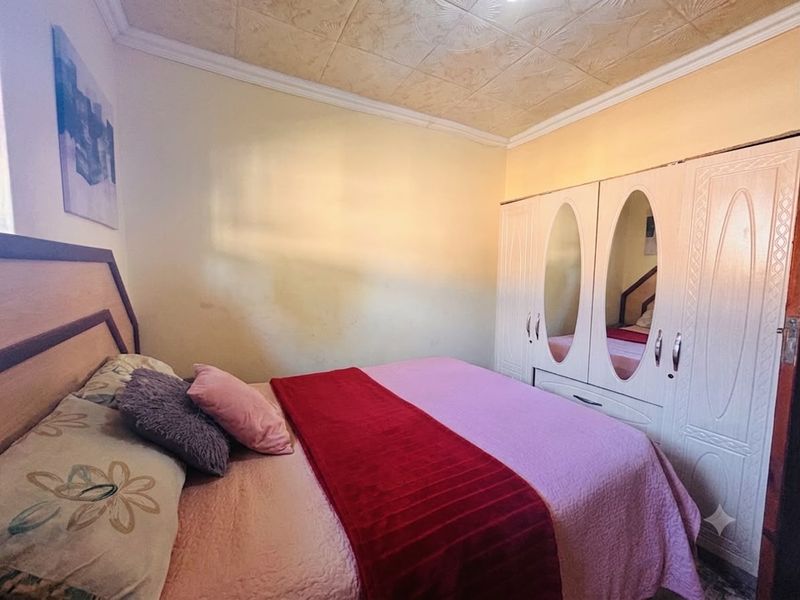 A bedroom featuring a built-in wardrobe with mirrored doors, decorative ceiling tiles, and crown molding, requiring cosmetic updates to the wall finishes.