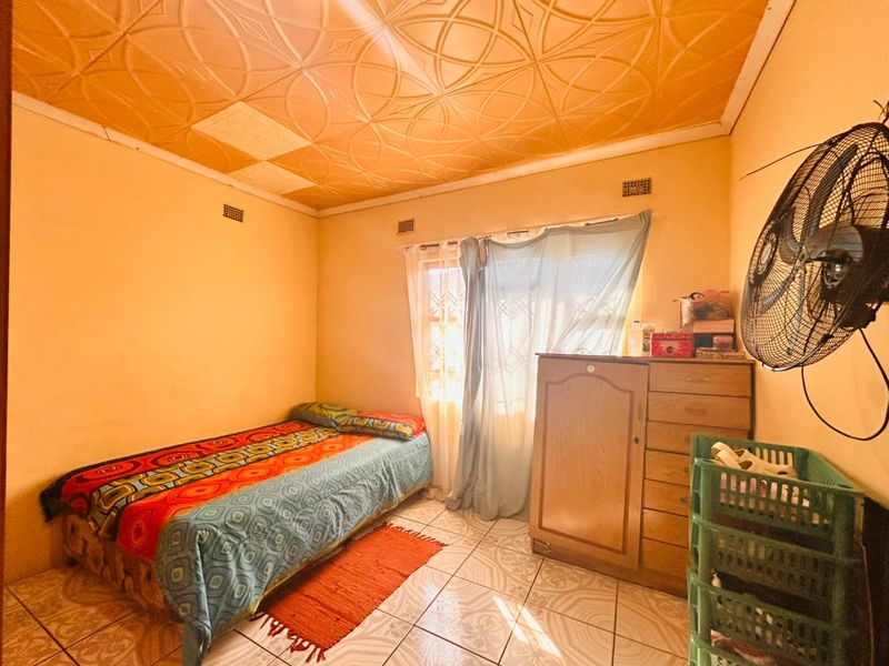 A bedroom featuring tiled flooring and decorative ceiling tiles, requiring cosmetic updates to improve the overall aesthetic and condition of the space.