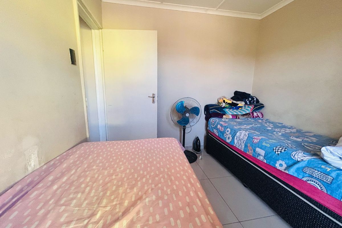 A functional bedroom featuring tiled flooring and a standard interior door, providing a simple and practical living space.