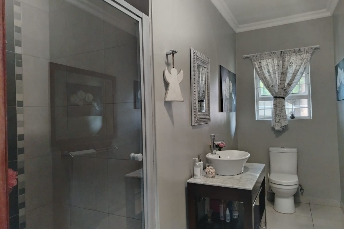 A modern bathroom featuring a glass-enclosed shower, a vessel sink set on a vanity, and a standard toilet with tiled flooring.