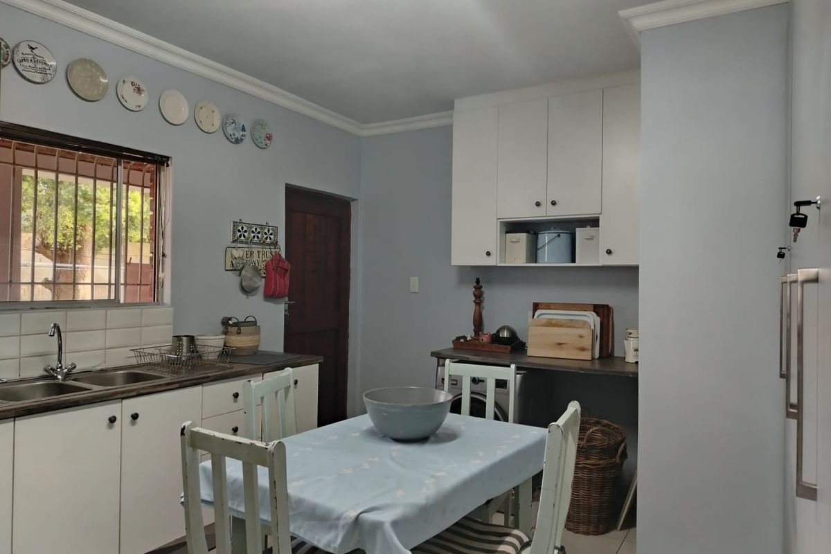 A functional kitchen featuring white cabinetry, a stainless steel sink, and a dedicated space for laundry appliances.