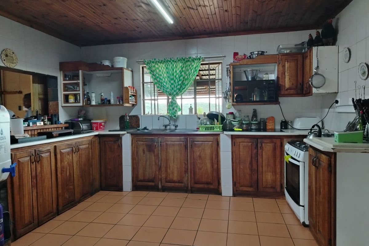 A functional kitchen featuring solid wood cabinetry, tiled flooring, and a timber-clad ceiling, offering a traditional aesthetic with ample storage space.
