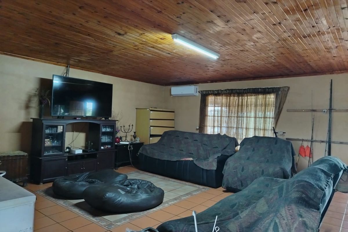 Spacious living room featuring a timber-clad ceiling, tiled flooring, and a wall-mounted air conditioning unit.