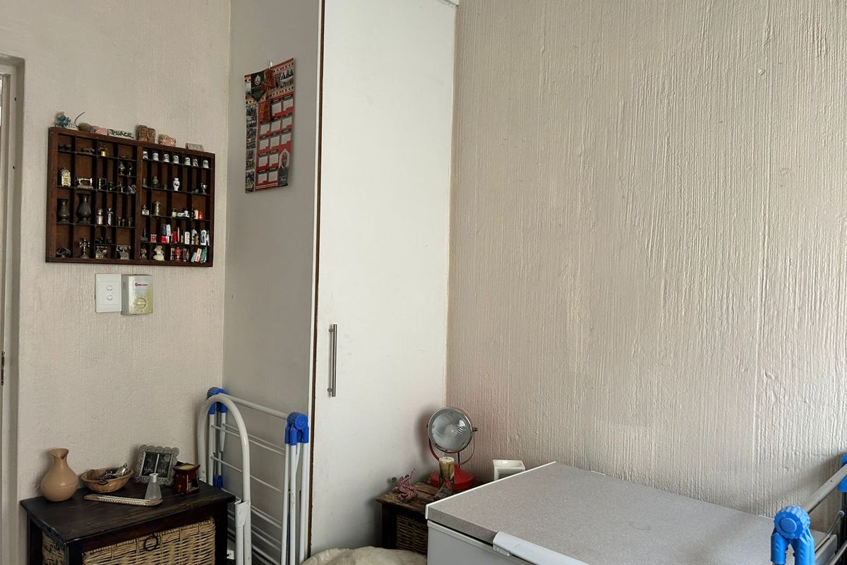 A bedroom corner featuring a built-in floor-to-ceiling wardrobe with a white finish.