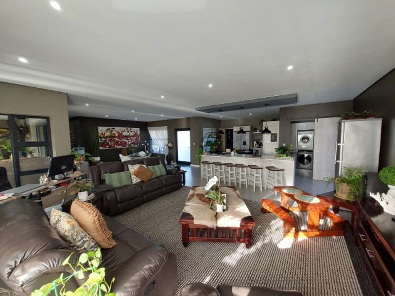 Spacious open-plan living area featuring a modern kitchen with a central island, recessed lighting, and seamless flow to the lounge and dining space.