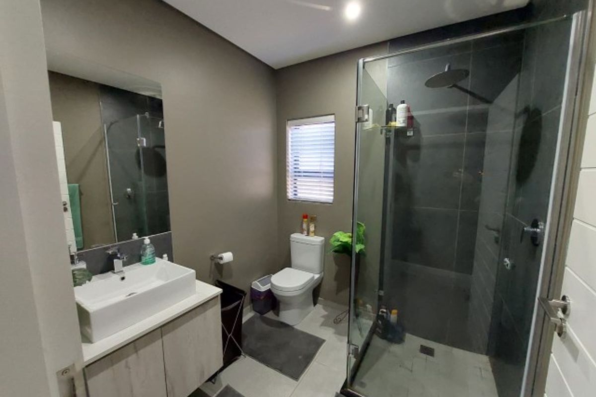 Modern bathroom featuring a vessel sink vanity, a glass-enclosed walk-in shower with a rain shower head, and neutral wall finishes.