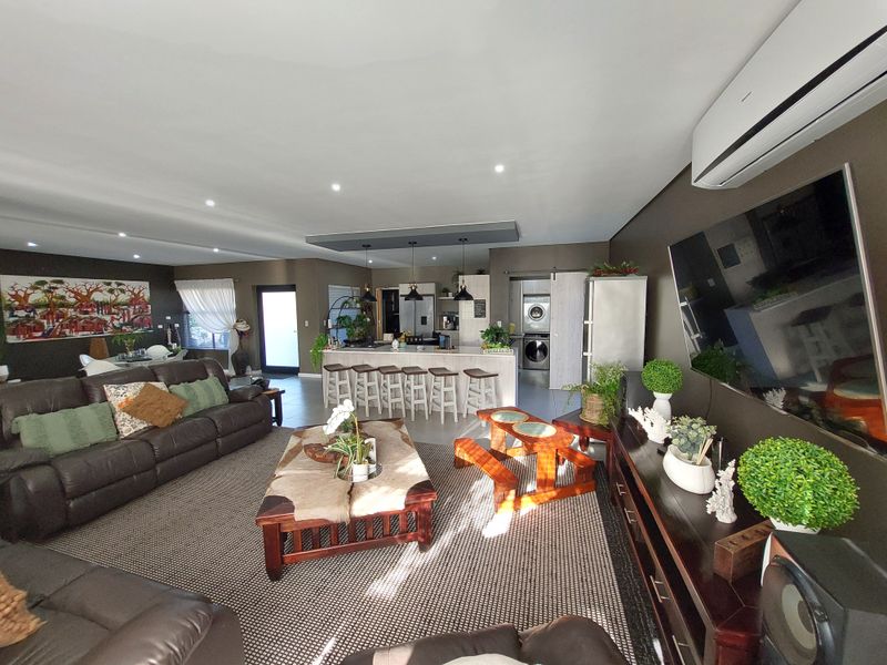 Spacious open-plan living area featuring a modern kitchen island, recessed lighting, and a split-system air conditioner, seamlessly connecting to the dining and laundry zones.