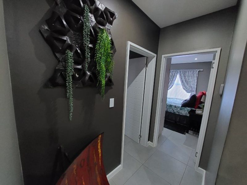 A well-maintained hallway featuring tiled flooring and neutral dark wall tones, providing access to adjacent rooms within the townhouse.