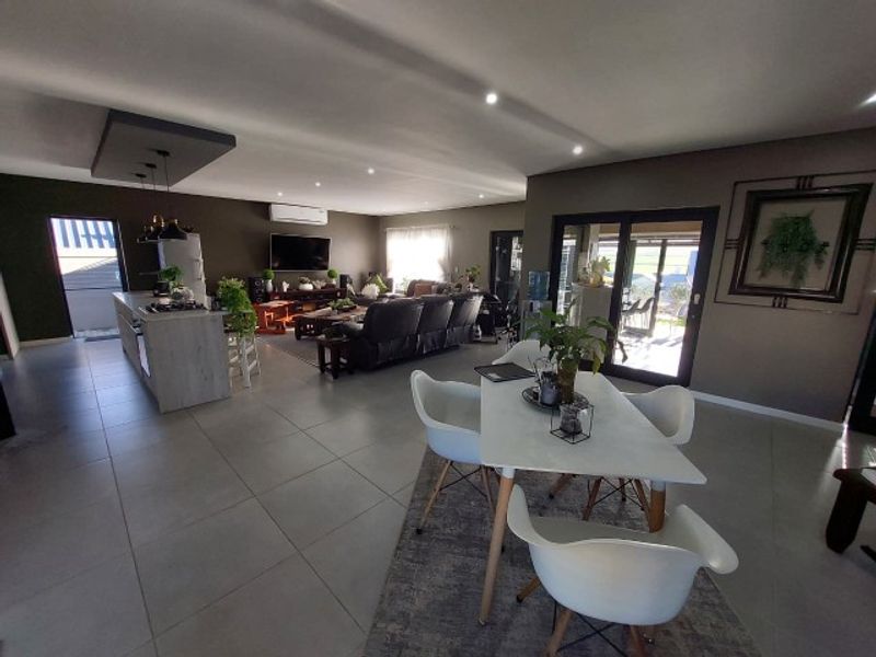 Spacious open-plan living area featuring a modern kitchen island, tiled flooring, recessed lighting, and seamless access to the outdoor patio through sliding glass doors.