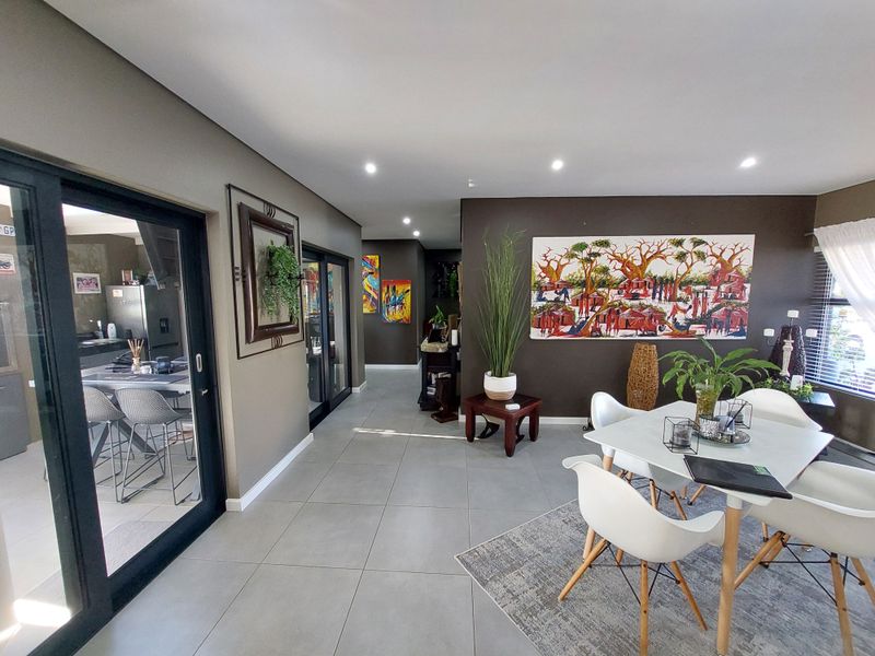 Spacious open-plan living and dining area featuring modern porcelain floor tiles, recessed downlighting, and large sliding glass doors providing seamless access to the kitchen.