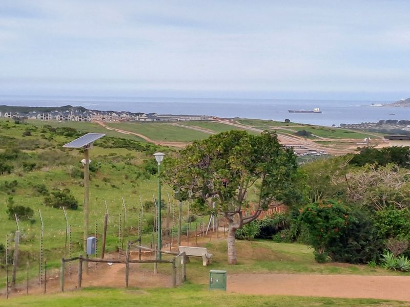 Elevated coastal view overlooking a residential development area with visible infrastructure including solar lighting and security fencing.