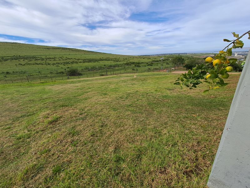 A wide-angle view of the vacant residential land featuring a grassy lawn, perimeter fencing, and expansive rolling landscape views.
