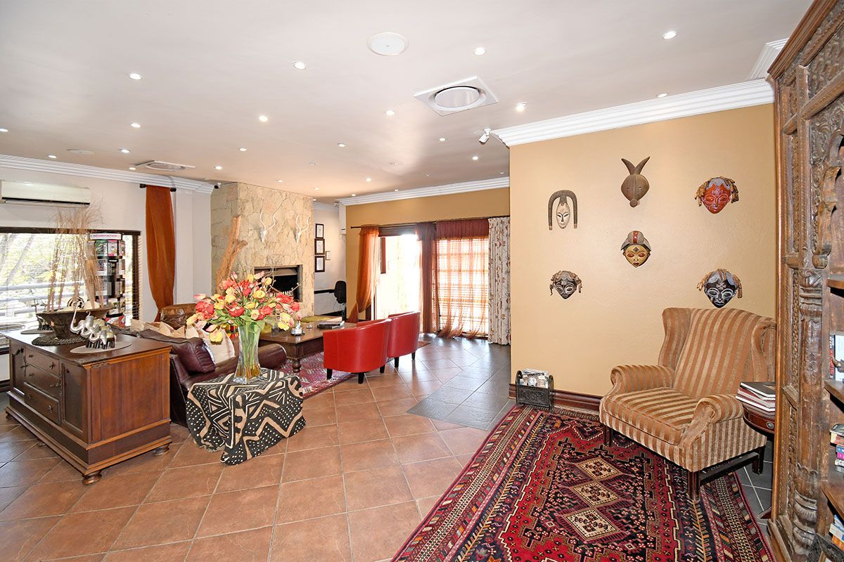 Spacious living area featuring tiled flooring, a stone-clad fireplace, recessed ceiling lighting, and integrated air conditioning units.