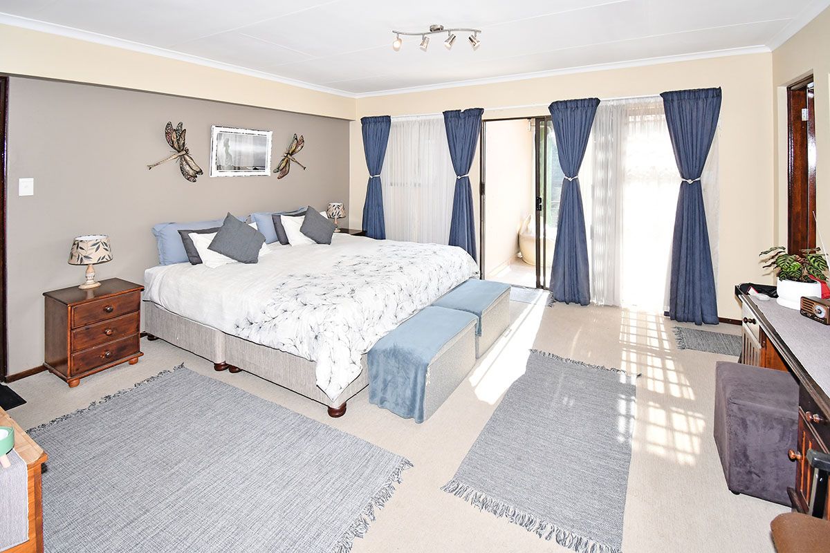 Spacious bedroom featuring neutral wall tones, carpeted flooring, and sliding glass doors providing direct access to an outdoor patio area.