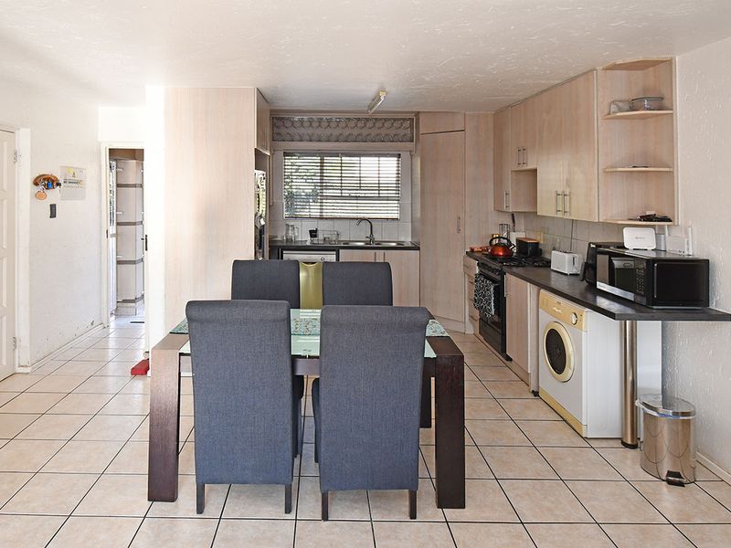Open-plan kitchen and dining area featuring light wood-tone cabinetry, tiled flooring, and integrated appliance spaces, offering a functional layout for daily living.
