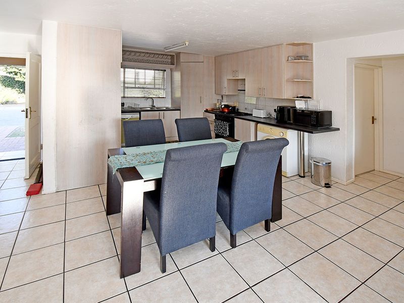 Open-plan kitchen and dining area featuring tiled flooring, light-toned built-in cabinetry, and direct access to the exterior.