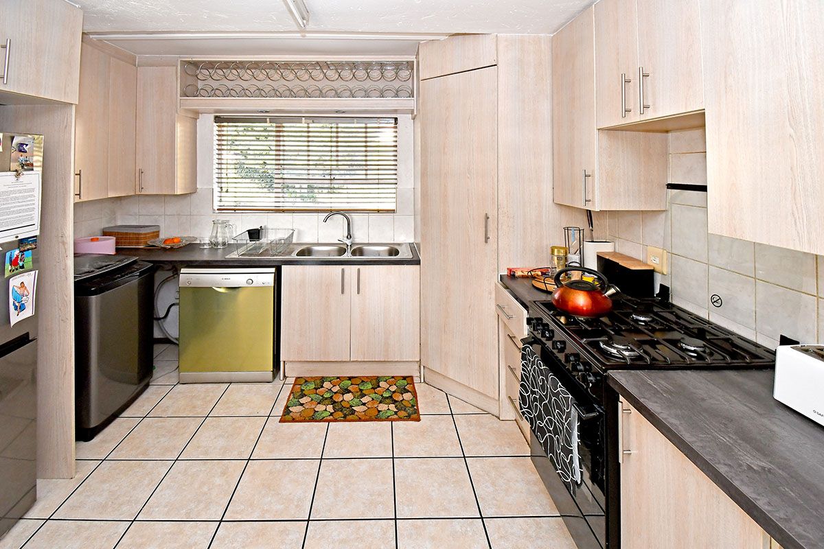 Functional kitchen featuring light wood-look cabinetry, tiled flooring, a gas hob, and a double bowl sink with a window view.