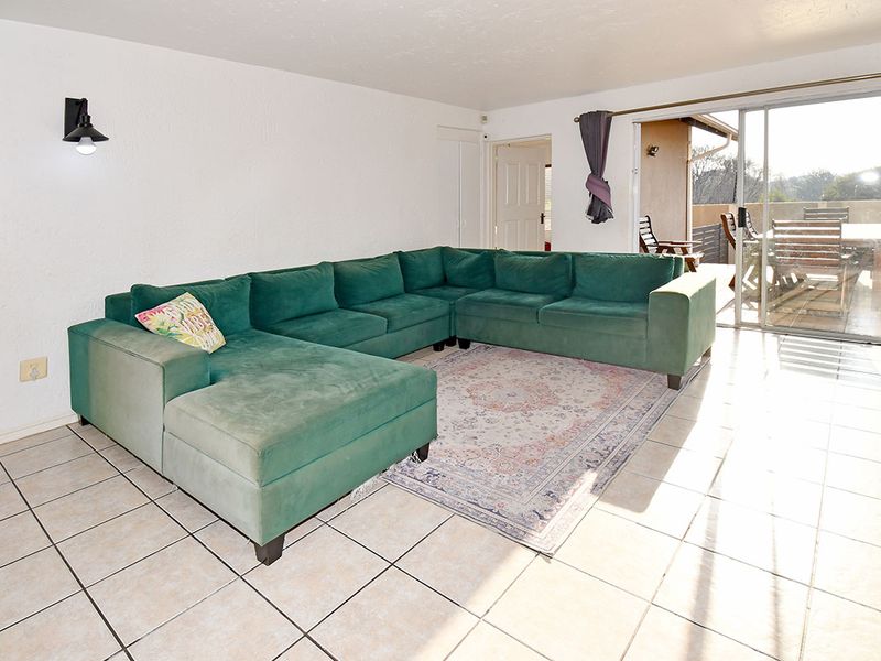 Spacious living room featuring ceramic floor tiles and a large sliding glass door providing direct access to the outdoor patio area.