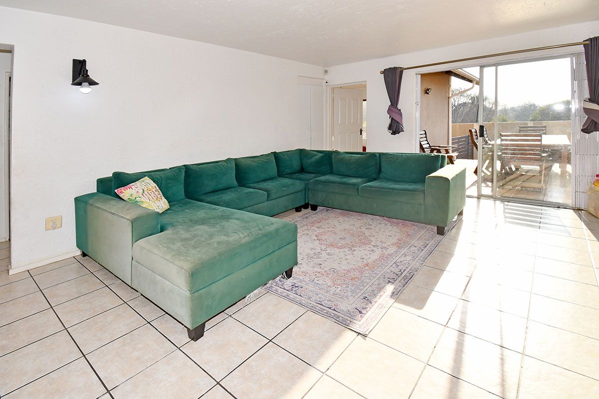 Spacious living room featuring ceramic floor tiles and a large sliding glass door providing direct access to the outdoor patio area.