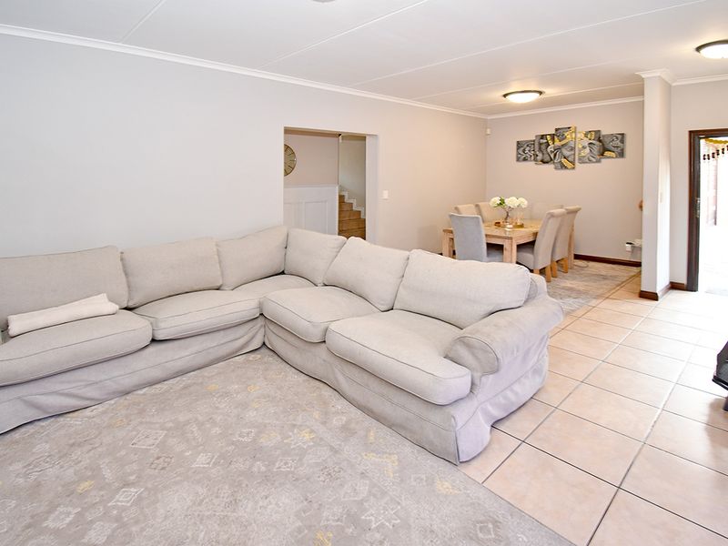 Spacious open-plan living and dining area featuring neutral wall tones, tiled flooring, and recessed ceiling details, providing a versatile layout for family living.