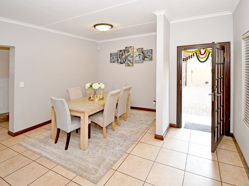 A bright dining area featuring neutral tiled flooring, a classic french door entrance, and clean wall finishes.