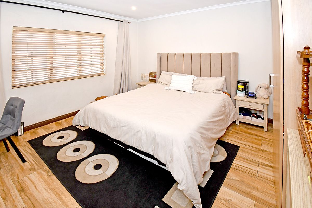 A well-maintained bedroom featuring wood-look tile flooring, neutral walls, and a built-in wardrobe, offering a comfortable and functional living space.