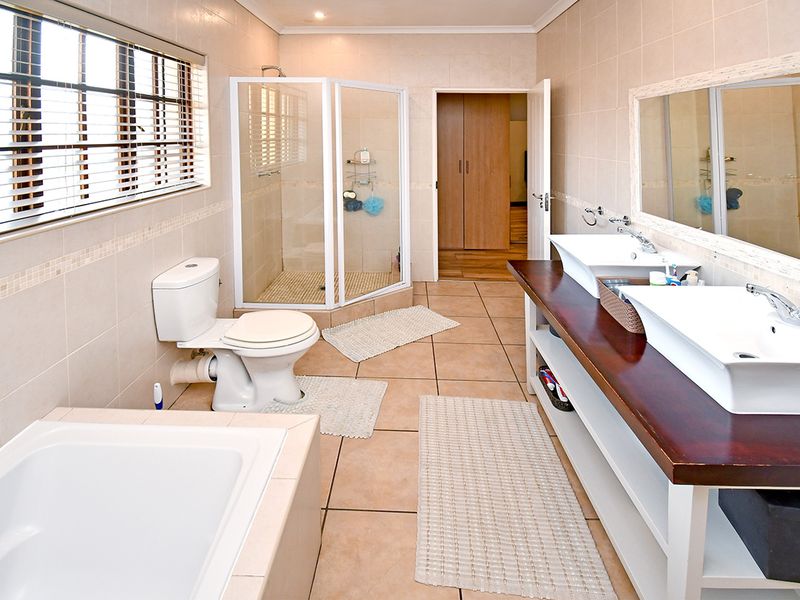 Spacious bathroom featuring a dual vanity with vessel sinks, a corner shower enclosure, and a built-in bathtub with neutral wall and floor tiling.