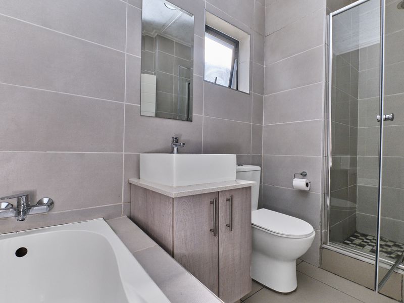 A modern bathroom featuring a built-in vanity with a vessel sink, a separate bathtub, and a glass-enclosed shower with tiled finishes.