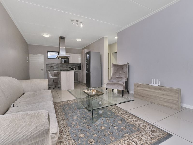 Open plan living area featuring a modern kitchen with built-in cabinetry, an extractor fan, and tiled flooring throughout.