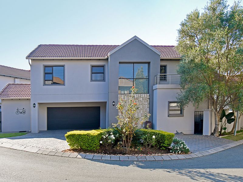 A well-maintained double-story residential home featuring a paved driveway, double garage, stone-clad facade, and a private balcony.