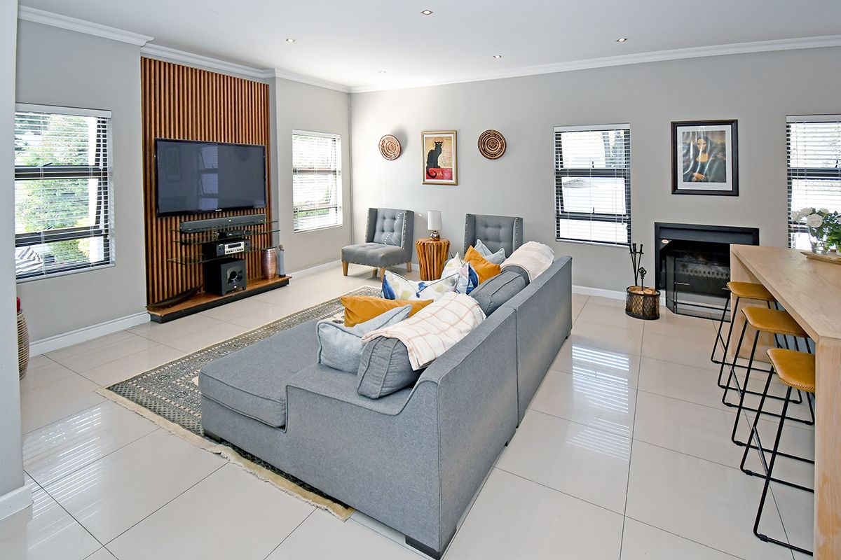 Spacious living room featuring large format floor tiles, a modern timber slat feature wall, and a built-in fireplace, creating a comfortable and contemporary atmosphere.