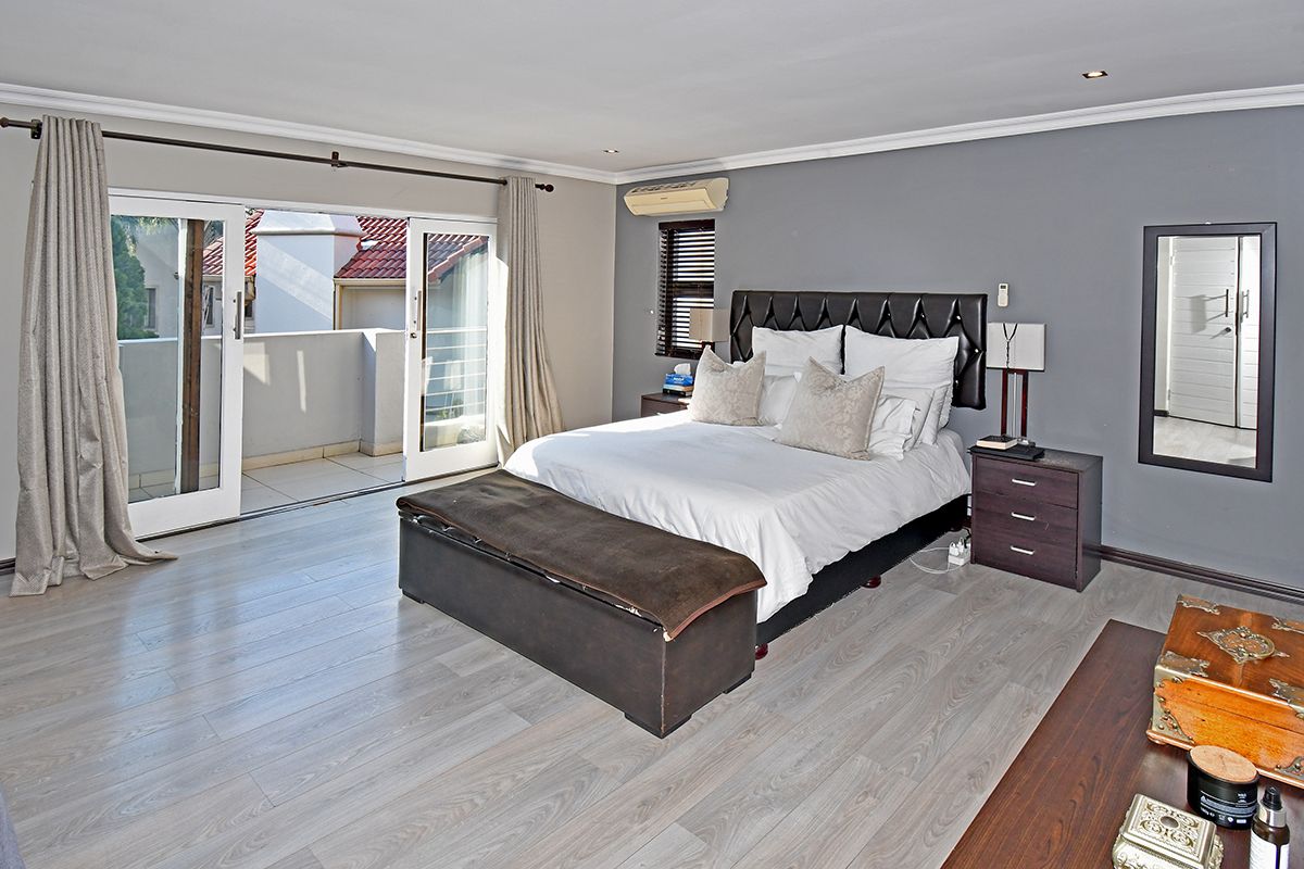 Spacious bedroom featuring light-toned laminate flooring, recessed lighting, and direct access to a private balcony through sliding glass doors.