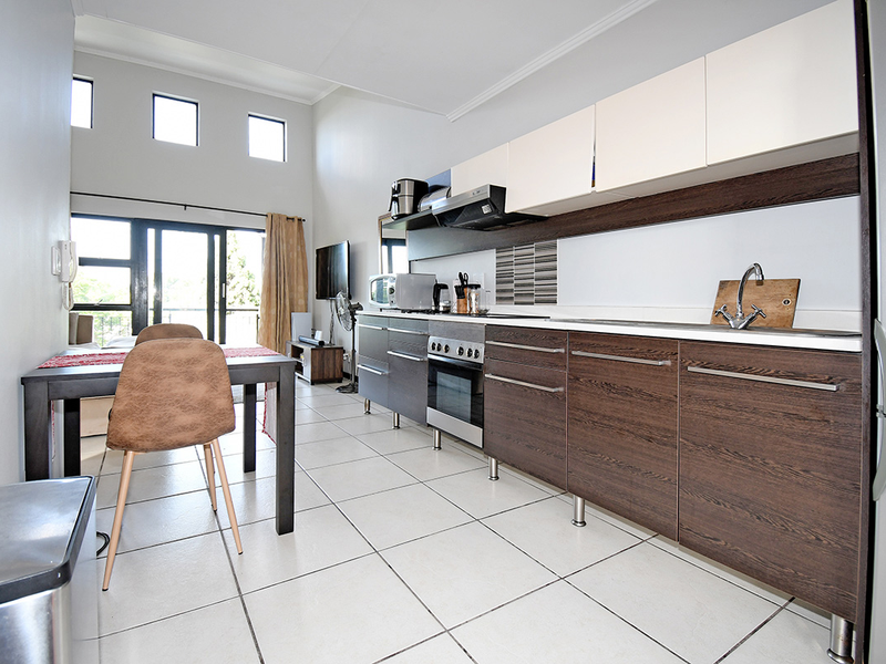 Modern open-plan kitchen and living area featuring sleek cabinetry, built-in appliances, tiled flooring, and large sliding doors leading to an outdoor space.