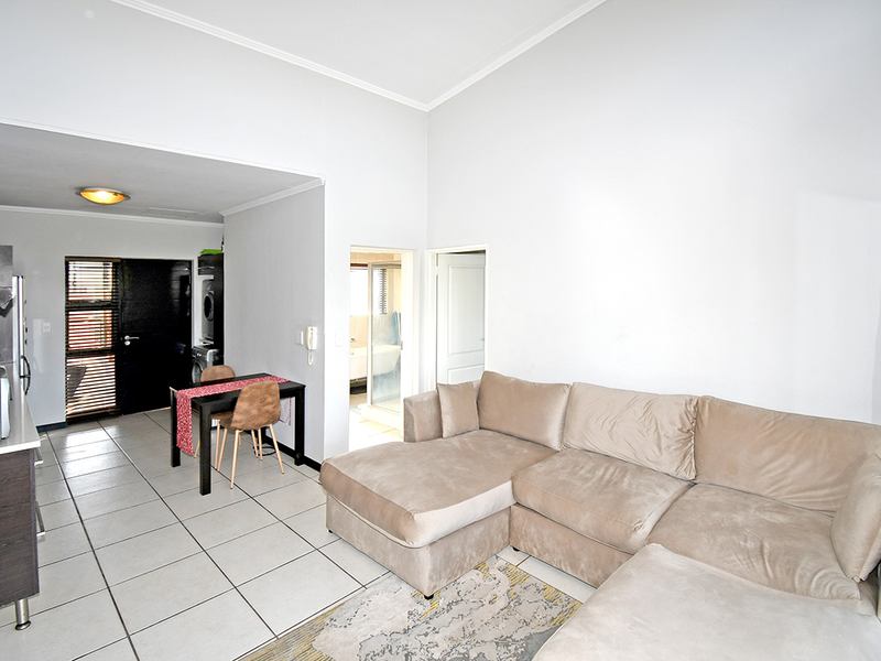 Open plan living area featuring tiled flooring, a compact kitchen space, and direct access to adjacent rooms.