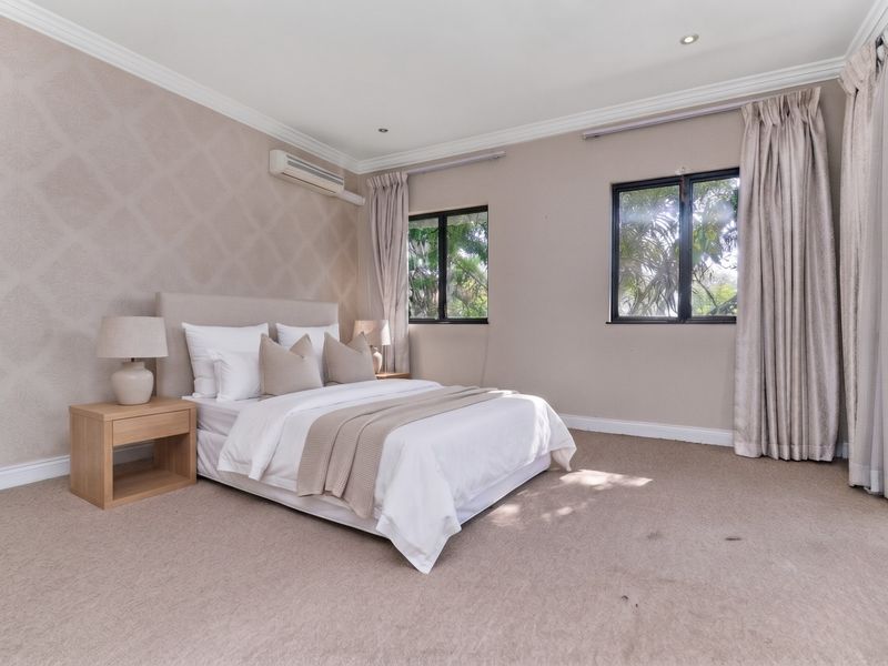 A spacious, well-maintained bedroom featuring neutral carpeting, crown molding, recessed lighting, and an integrated air conditioning unit.