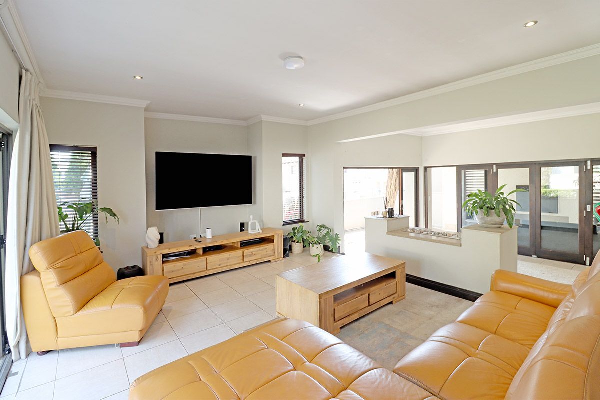 Spacious living room featuring neutral tiled flooring, recessed downlighting, and large sliding glass doors providing seamless access to the outdoor area.