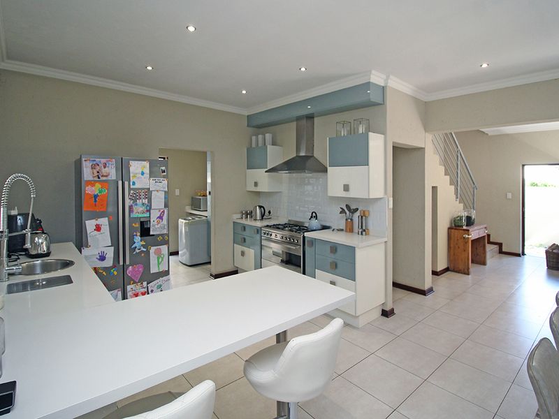 Modern kitchen featuring a gas hob, extractor fan, built-in oven, and a breakfast bar, seamlessly connected to the living area and staircase.