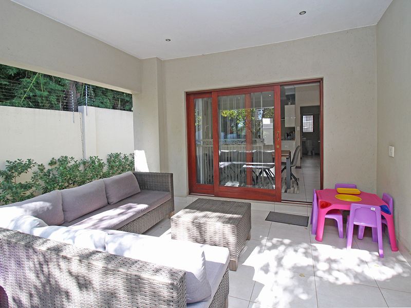 A covered patio area featuring tiled flooring, recessed lighting, and sliding glass doors providing access to the interior living space.