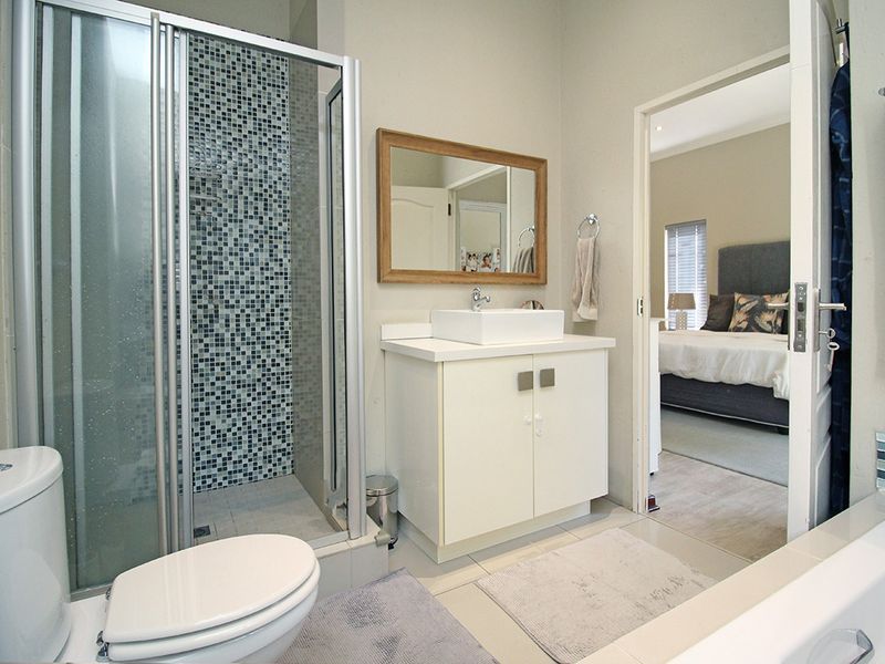 A well-maintained bathroom featuring a glass shower enclosure with mosaic tiling, a modern vanity with a vessel sink, and a separate bathtub.