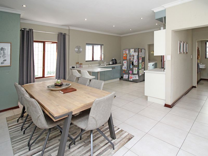 Open-plan living and dining area featuring tiled floors, recessed lighting, and a functional kitchen with built-in cabinetry and island.