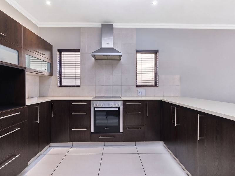 A modern, well-maintained kitchen featuring dark wood cabinetry, stone countertops, and integrated stainless steel appliances, offering a clean and functional workspace.