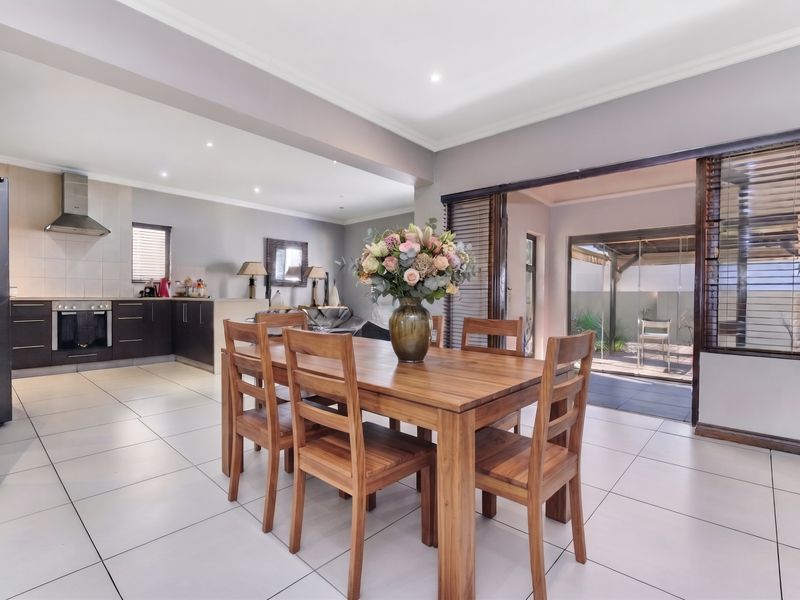 Spacious open-plan living and dining area featuring tiled floors, recessed lighting, and a modern kitchen with built-in appliances, leading to an outdoor patio.