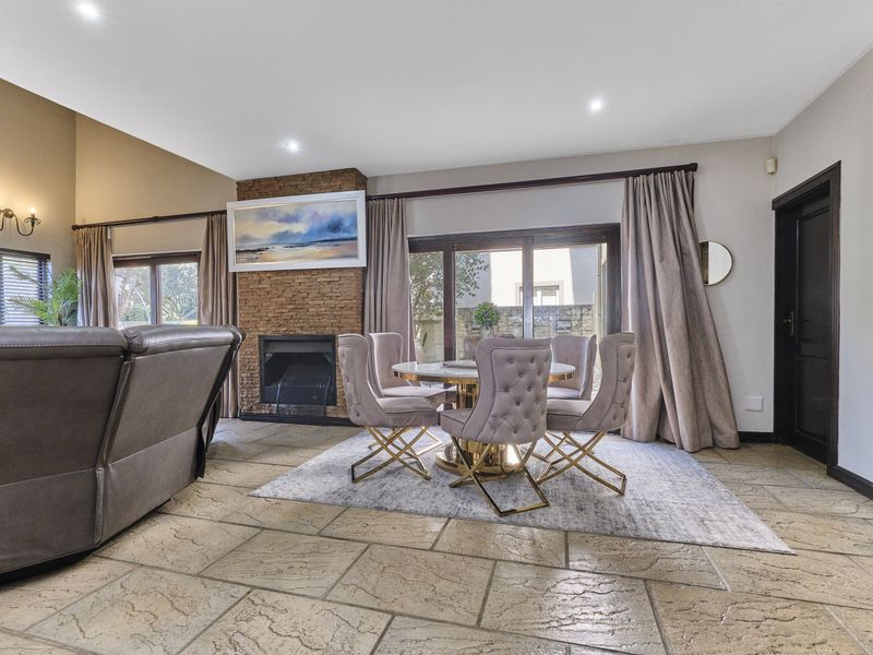Spacious open-plan living and dining area featuring a stone-clad fireplace, vaulted ceilings, and large sliding glass doors leading to the exterior.