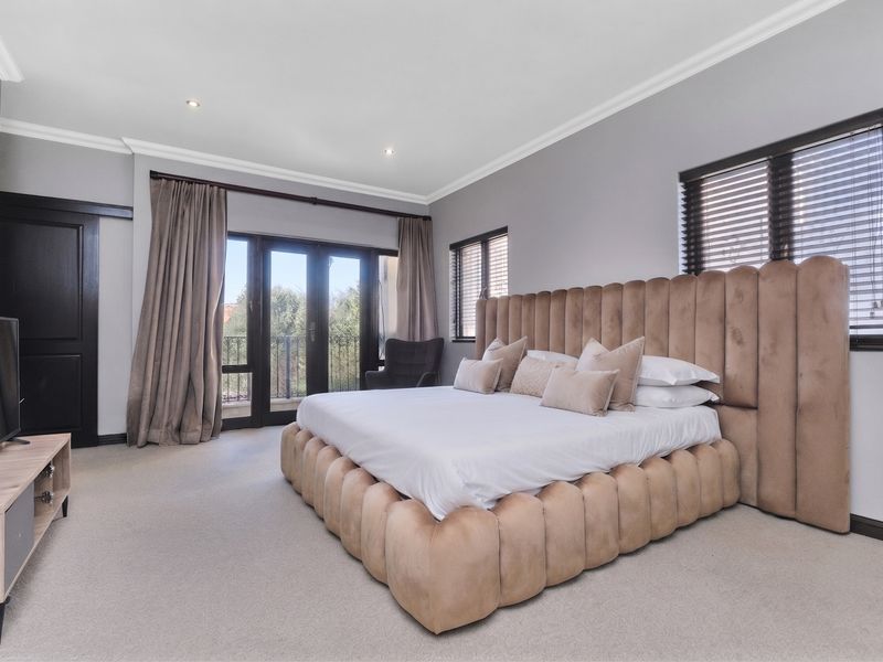 Spacious bedroom featuring neutral carpeting, crown molding, recessed lighting, and direct access to a private balcony through glass sliding doors.
